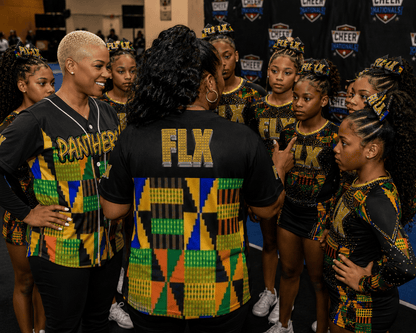 Group of cheerleaders in matching uniforms with 'FLX' branding, receiving instructions for cheer competition.